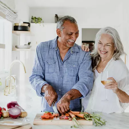 smiling older couple chopping at kitchen counter
