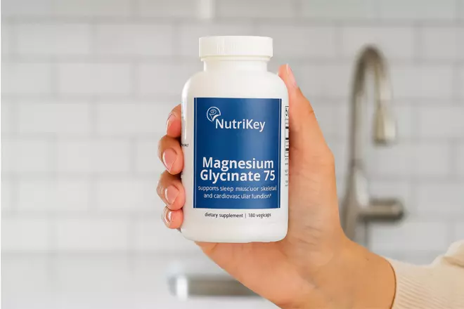 hand holding a bottle of NutriKey Magnesium Glycinate 75