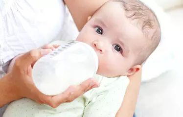 Baby drinking baby formula from bottle