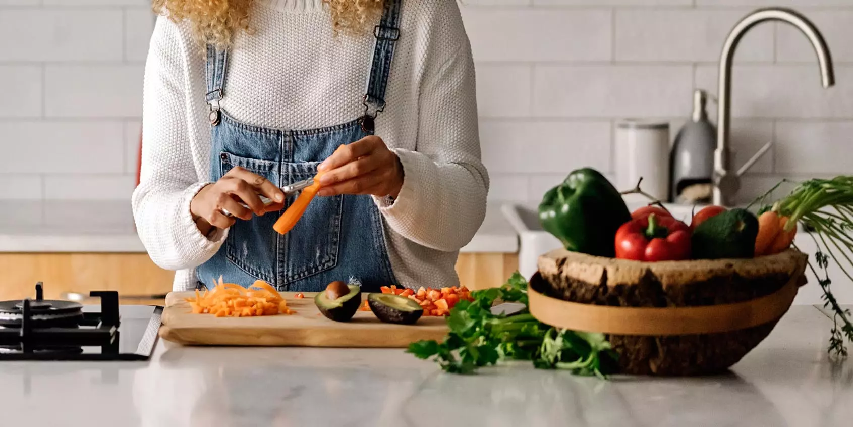 a woman peeling carrots at a wooden cutting board