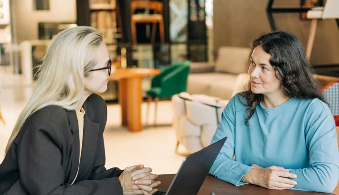 2 women at a table with a laptop discussing insurance coverage