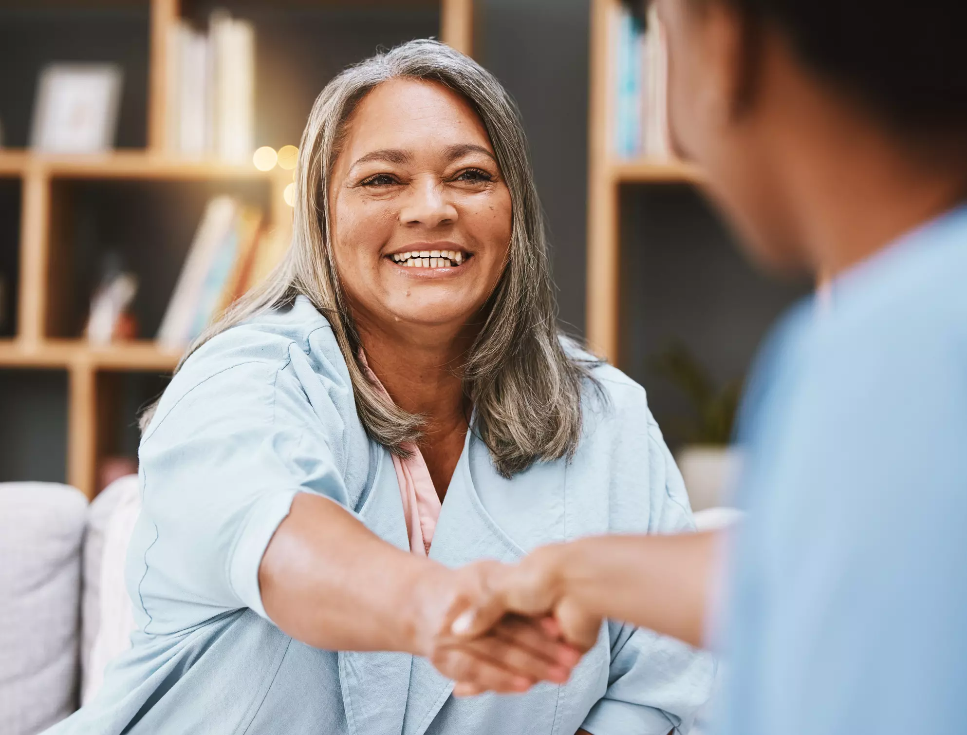 a smiling woman shaking hands with another person