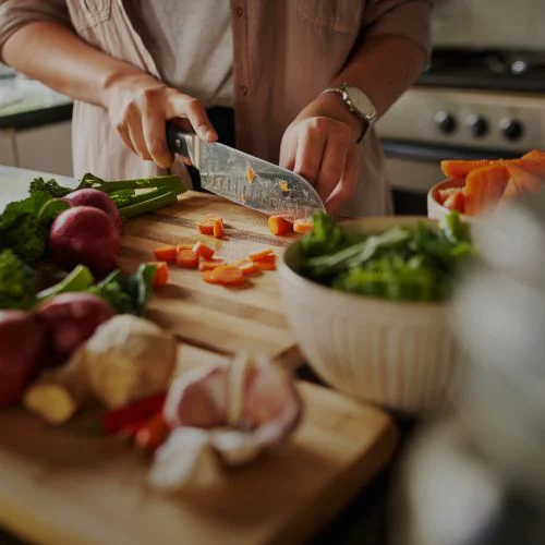a person chopping veggies on a wooden cutting board
