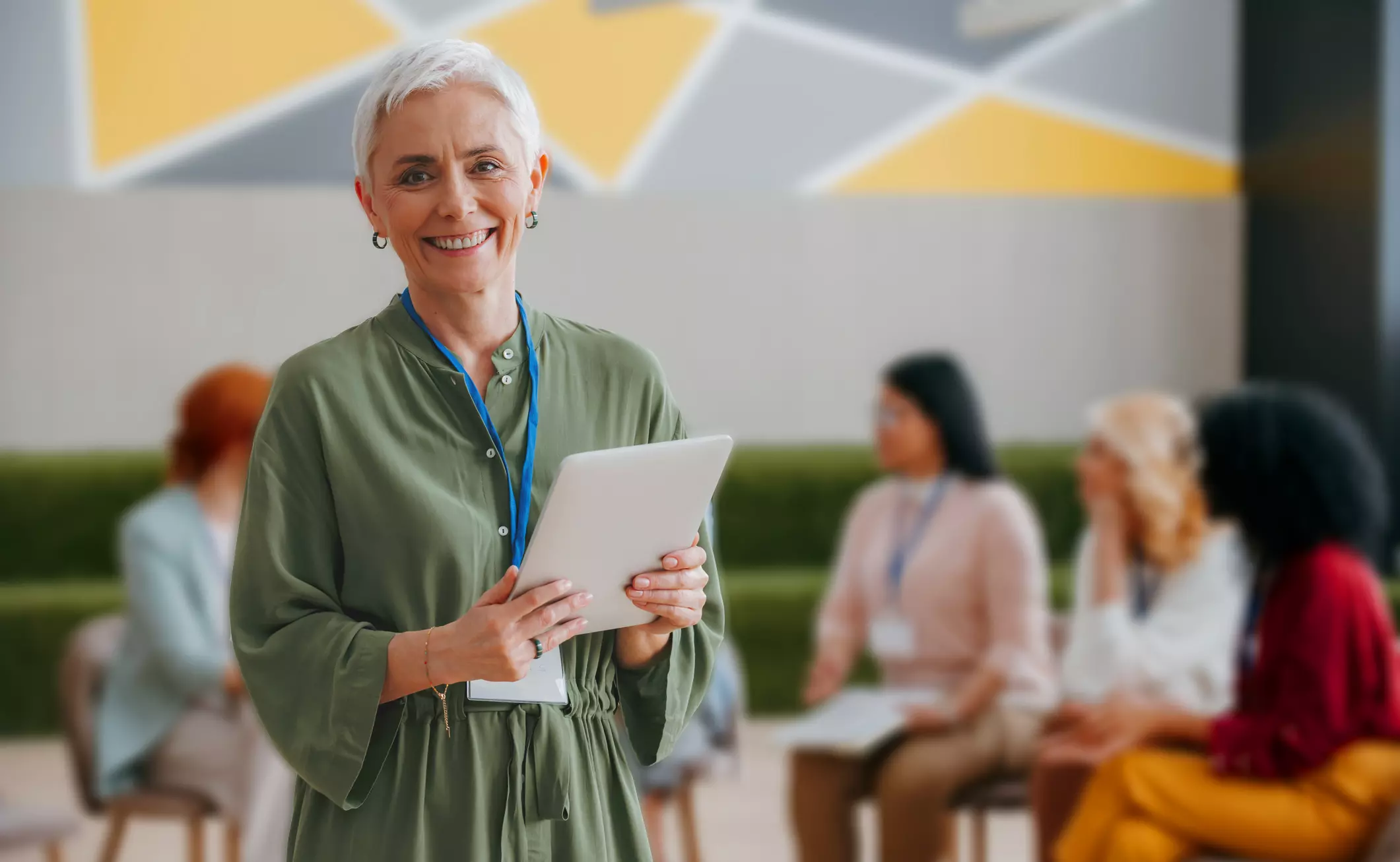 older woman smling at the camera holding an ipad